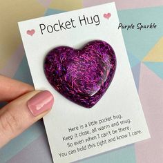 a purple heart shaped brooch sitting on top of a piece of paper next to a card