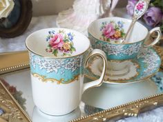 two tea cups and saucers on a tray