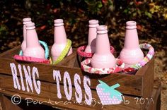 four pink soda bottles in a wooden crate with the word ring toss on it's side