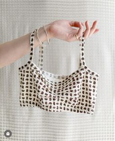 a woman's hand holding onto a white and brown polka doted bralet