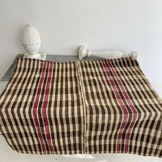 a brown and white checkered blanket sitting on top of a metal table next to a vase