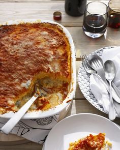 a casserole dish on a wooden table with silverware