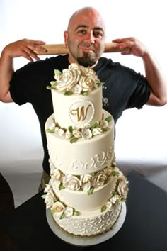 a man standing next to a three tiered cake with roses on it and the letter n