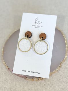 "Welcome to KatieCollinsXO. Get ready for summer with these darling gold, wood and white circle earrings sporting a bit of minimalist charm, right on trend for 2024! Neutral, fun and fashionable, they feature textured white clay circles and gold hoops that hang from round wood earring backs. Neutral enough to wear with almost anything, they also make a great gift for any minimalist in your life! Truly one-of-a-kind, all of my earrings are lovingly handmade by me with extremely lightweight polymer clay, and come with stainless steel backs. I also offer FREE shipping on all orders over $35 as well as a FREE gift with any purchase! DETAILS * Handmade of polymer clay. * Gold and white circles with wood earring backs. * Stainless steel backs. * 1.25 inches long x 0.75 inches wide. * FREE shippi Nickel-free White Circle Hoop Earrings, Nickel Free White Circle Hoop Earrings, Textured Round Earrings For Gifts, White Handmade Circular Earrings, Handmade White Circular Earrings, Everyday Round Textured Earrings, Everyday Textured Round Earrings, Nickel-free White Circular Earrings, Nature-inspired Nickel Free White Earrings