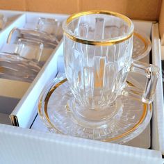 an empty glass cup and saucer sitting in a box on top of a table