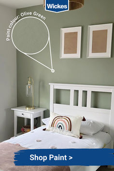 a bedroom with green walls, white bedding and pictures on the wall above it