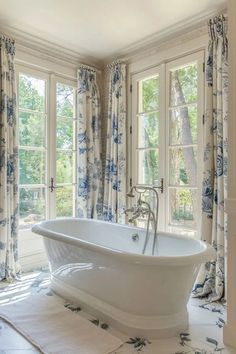 a white bath tub sitting next to two windows