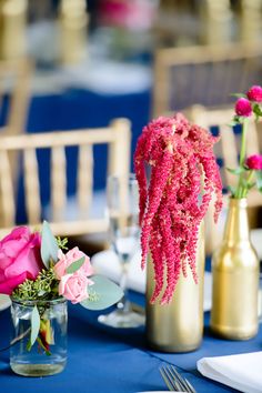 the table is set with pink flowers and gold vases