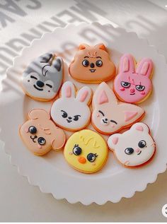 a white plate topped with cookies covered in different types of animal face designs on top of each other