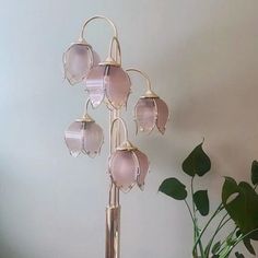 a pink flower lamp sitting on top of a table next to a potted plant