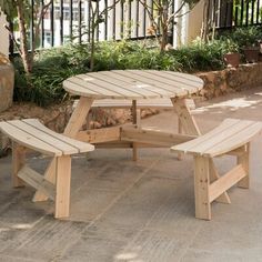 a wooden picnic table sitting on top of a cement ground next to a stone wall