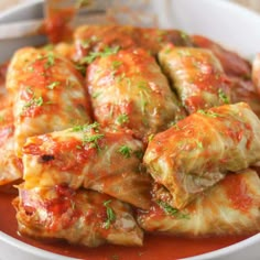 stuffed cabbage rolls with marinara sauce and parsley on top in a white bowl