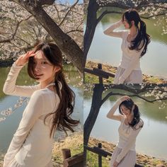 a woman in white dress standing next to a tree and posing for the camera with her hands on her head