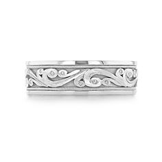 a white gold wedding band with swirly designs on the sides and diamonds in the middle