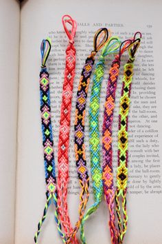 four different colored bracelets on top of an open book