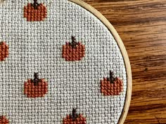 a cross stitch pumpkin pattern on a wooden table