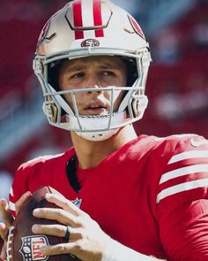 a close up of a person wearing a football uniform and holding a ball in his hands