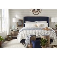 a bedroom with white walls, blue bedding and wicker baskets on the floor