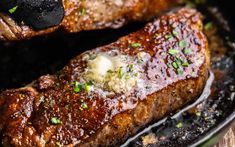 two steaks covered in sauce and parmesan cheese on top of a grill