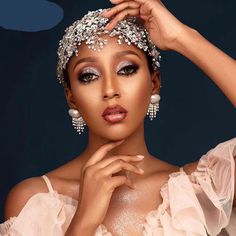 a woman in a white dress is posing with her hands on her head and wearing jewelry