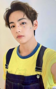 a young man wearing overalls and yellow shirt