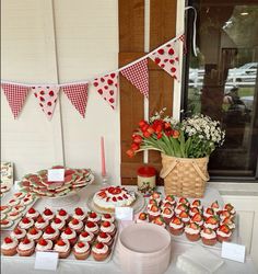 a table topped with lots of cupcakes covered in frosting and strawberries