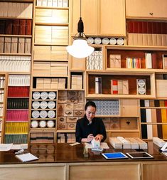 a woman sitting at a desk in front of a book shelf filled with lots of books