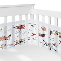 a white crib with airplanes and clouds on it