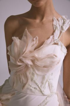 a woman in a white dress with flowers on it's shoulder and one hand on her hip