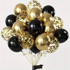 a bunch of black and gold balloons with confetti