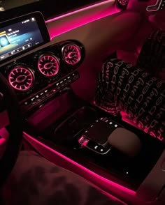 the interior of a car is lit up with pink lights and decorative pillows, along with other accessories