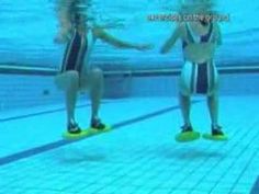 two women in swimsuits standing on the side of a swimming pool with their hands together