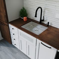 a kitchen with white brick walls and wooden counter tops, black faucet on the sink