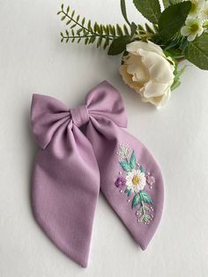 two bows with flowers on them sitting next to each other, one is purple and the other is white