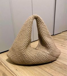 a woven bag sitting on the floor in front of a wall with white panels behind it