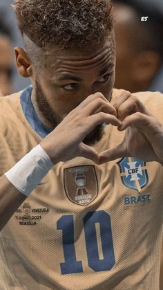 a soccer player making a heart sign with his hands while standing in front of an audience