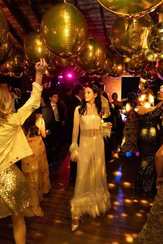 a group of people standing around each other in a room with disco balls hanging from the ceiling