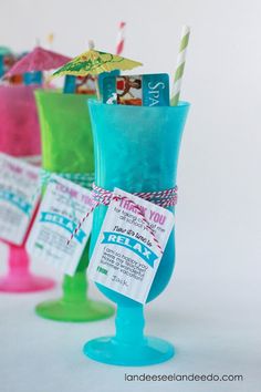 three different colored drinks in plastic cups with tags attached to the sides and straws sticking out of them