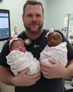 a man holding two newborn babies in his arms