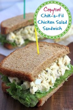 chicken salad sandwich cut in half on a cutting board with a green and yellow sticker