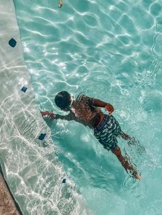 a man swimming in a pool with blue water