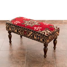 a red ottoman sitting on top of a tile floor