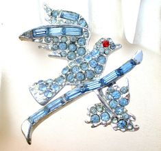 Figural Jewelry - This is a silver rhodium plated brooch of a blue rhinestone bird sitting on on a branch with leaves. It measures 1.7" by 1.5". Branch With Leaves, Bird On A Branch, Bird Sitting, Figural Jewelry, Blue Rhinestones, Blue Bird, Rhodium Plated, Brooch Pin, Plating