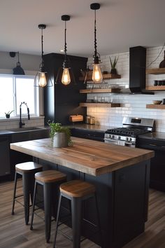 a kitchen island with stools and lights hanging from it's ceiling over the stove