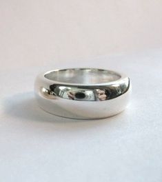 This is a beautiful, heavy sterling band ! This ring is very comfortable and makes a statement on it's own. This piece is great to wear everyday. It is ever so slightly tapered and measures 7.5mm to 8mm wide. The depth is 3mm. This ring can be custom made up to a size 8. This ring can be ordered in silver, gold and platinum. Polished Dome Ring With Thick Band For Promise, Classic Sterling Silver Wide Band Promise Ring, Everyday Sterling Silver Wide Band Ring With Polished Finish, Classic Wide Band Dome Ring For Promise, Classic Dome Ring With Wide Band For Promises, Classic Sterling Silver Wide Band Ring For Everyday, Classic Thick Band Ring In Sterling Silver, Silver Dome Ring With Round Band For Everyday, Classic Wide Band Ring In Sterling Silver