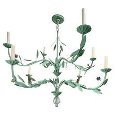 a green chandelier with six candles hanging from it's arms and leaves