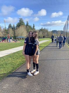 two girls are standing on the side walk