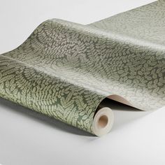 a roll of green wallpaper with leaves on the top and bottom, sitting on a white surface