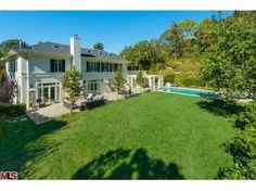 an aerial view of a house with a swimming pool in the yard and trees surrounding it