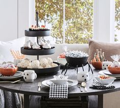 a table topped with plates and bowls filled with desserts next to a large window